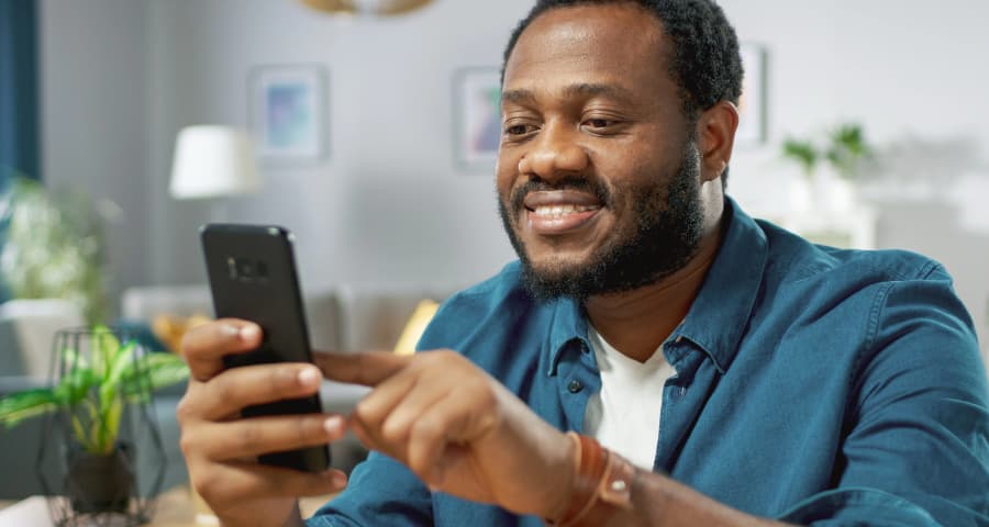Man at home interacting with a home security app on his smartphone